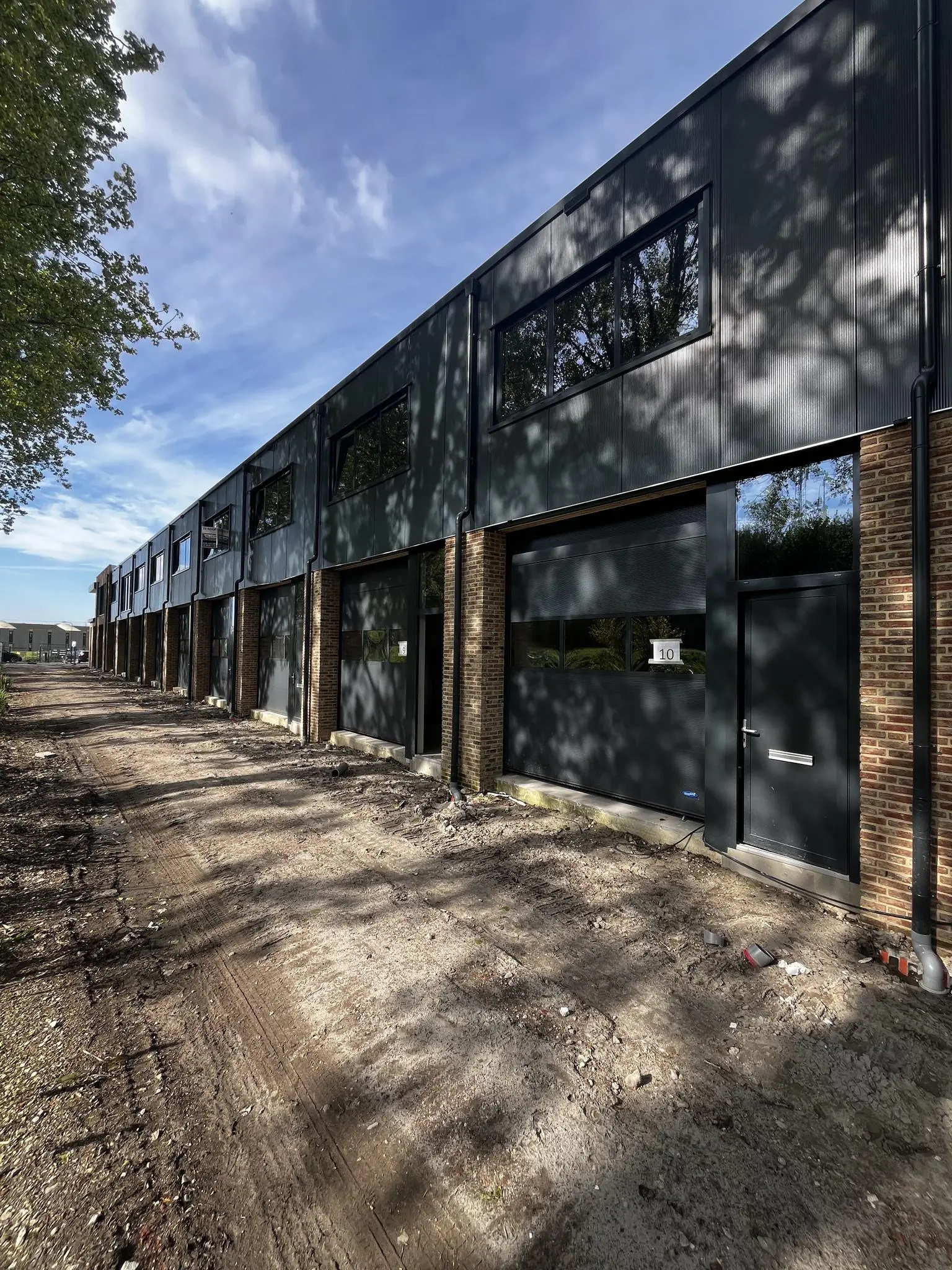 Rij nieuwbouw bedrijfsunits aan de Broekdijk West met moderne gevels en onverharde toegangsweg.